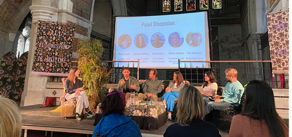 Panellists sat on stage with a screen behind them reading 'Panel Discussion'. 