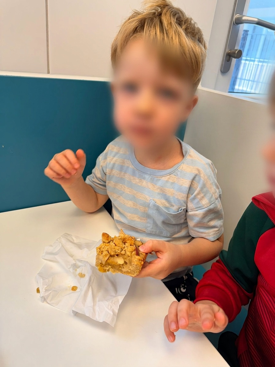 Junge der elbzwerge Kita Stellingen hält ein Stück Apfelkuchen ohne Zuckerzusatz