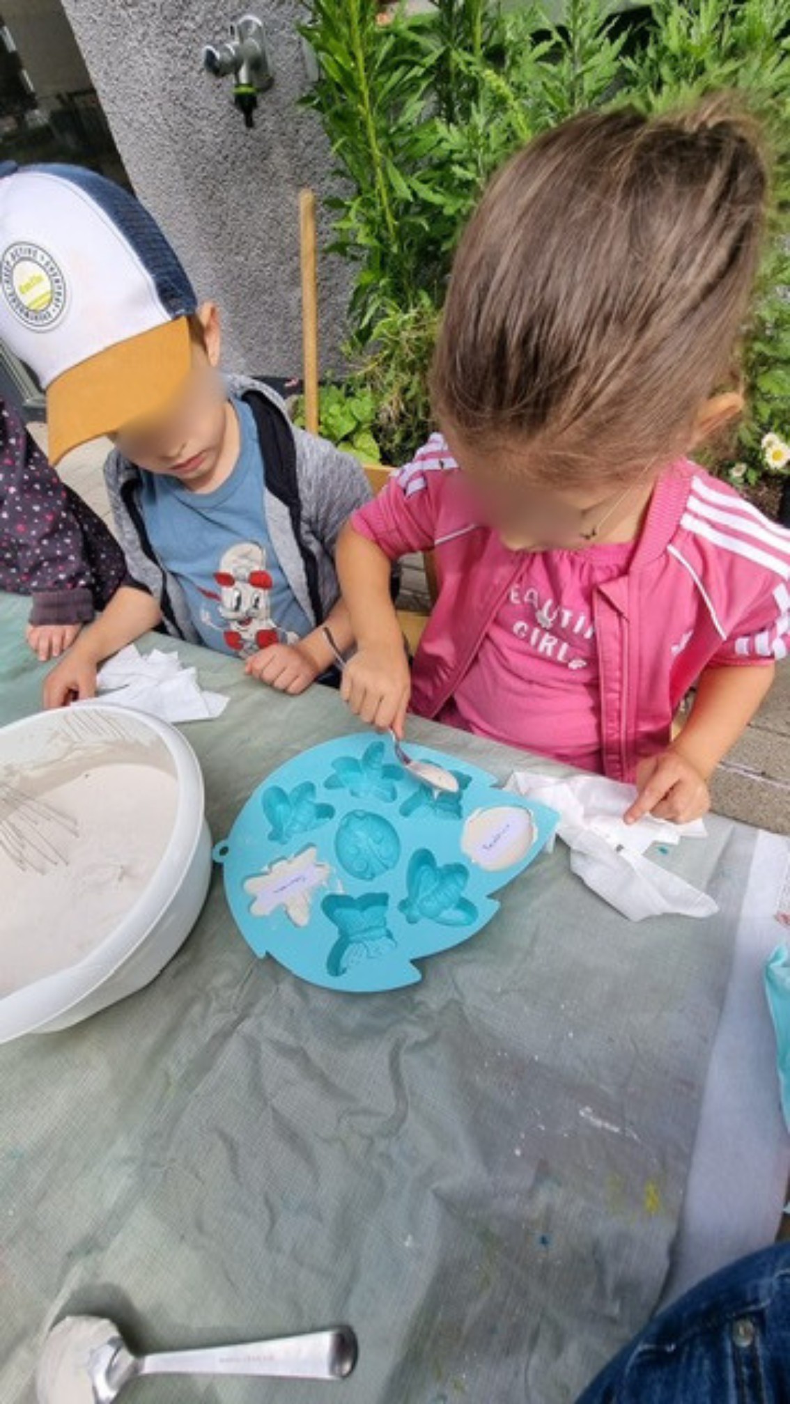 Kinder der elbzwerge Kita Stellingen gießen gemeinsam Modellgips in Insektenformen im Garten