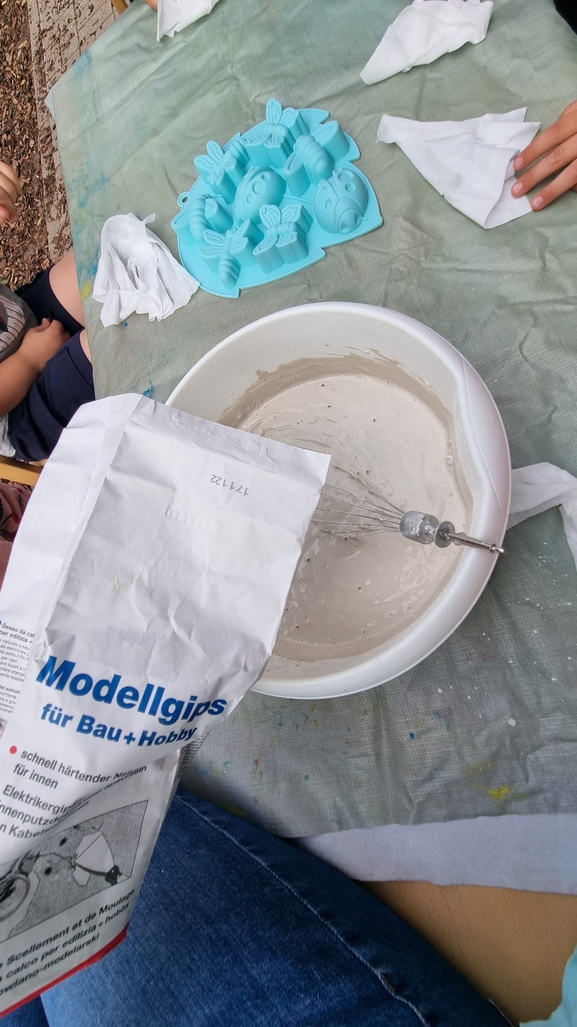 Modellgips wird in der elbzwerge Kita Stellingen draußen in einer Schüssel angerührt, daneben eine blaue Insektenform