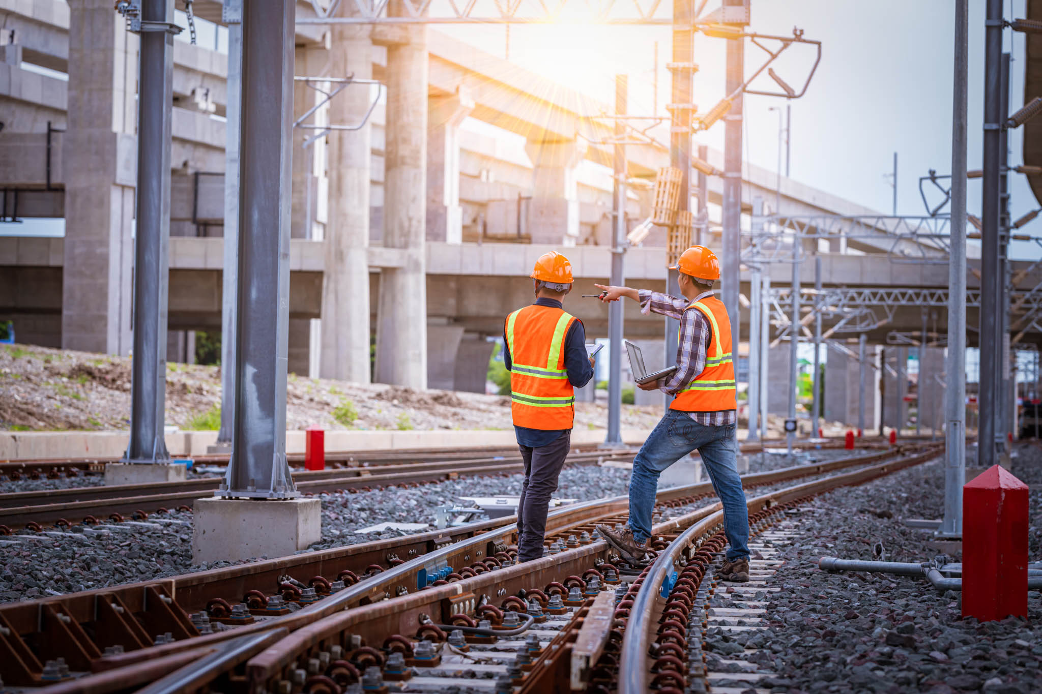 A close up of train tracks with a construction worker doing work on the tracks in the background.