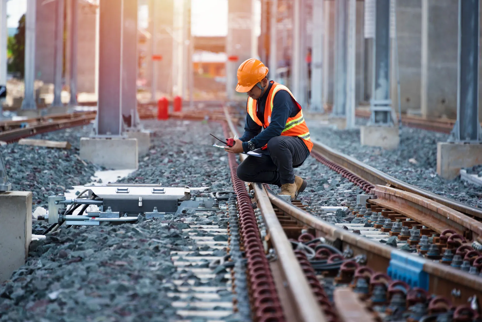 A man wearing a health and safety uniform working on railway lines.