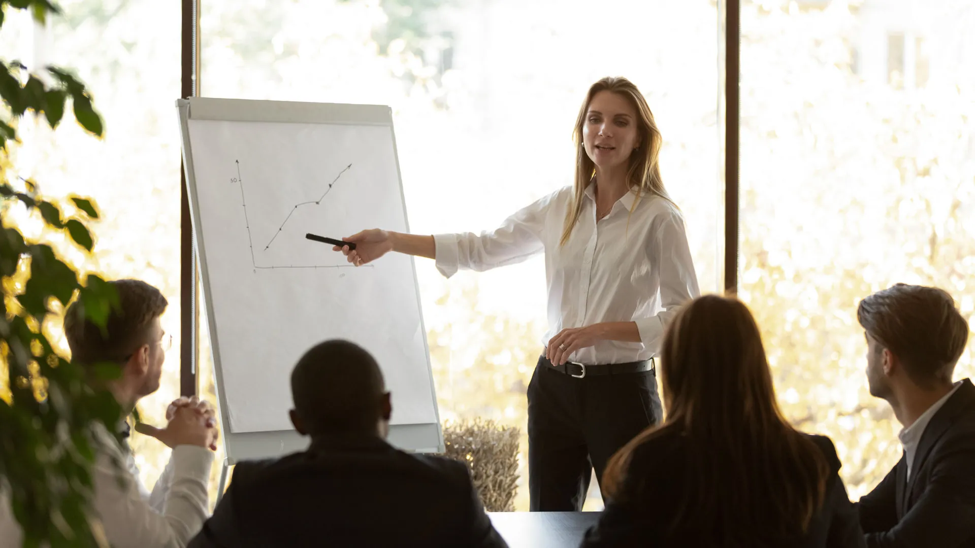 A meeting being conducted with a women pointing at a presentation.
