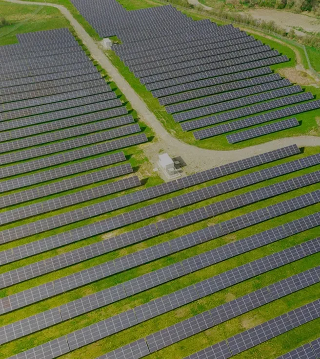 Aerial view of a solar farm with multiple rows of solar panels installed on green grass.