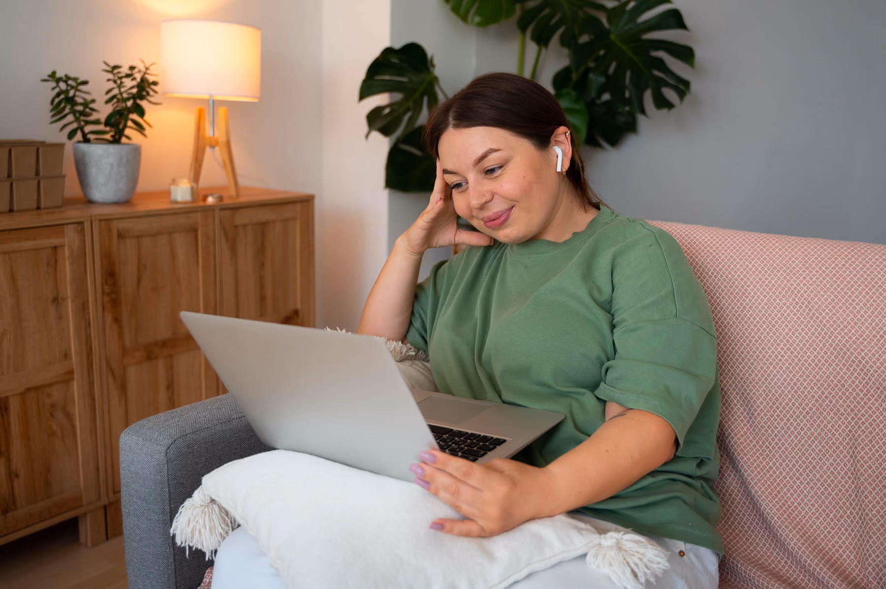 A woman sitting on a couch using a laptop computer.