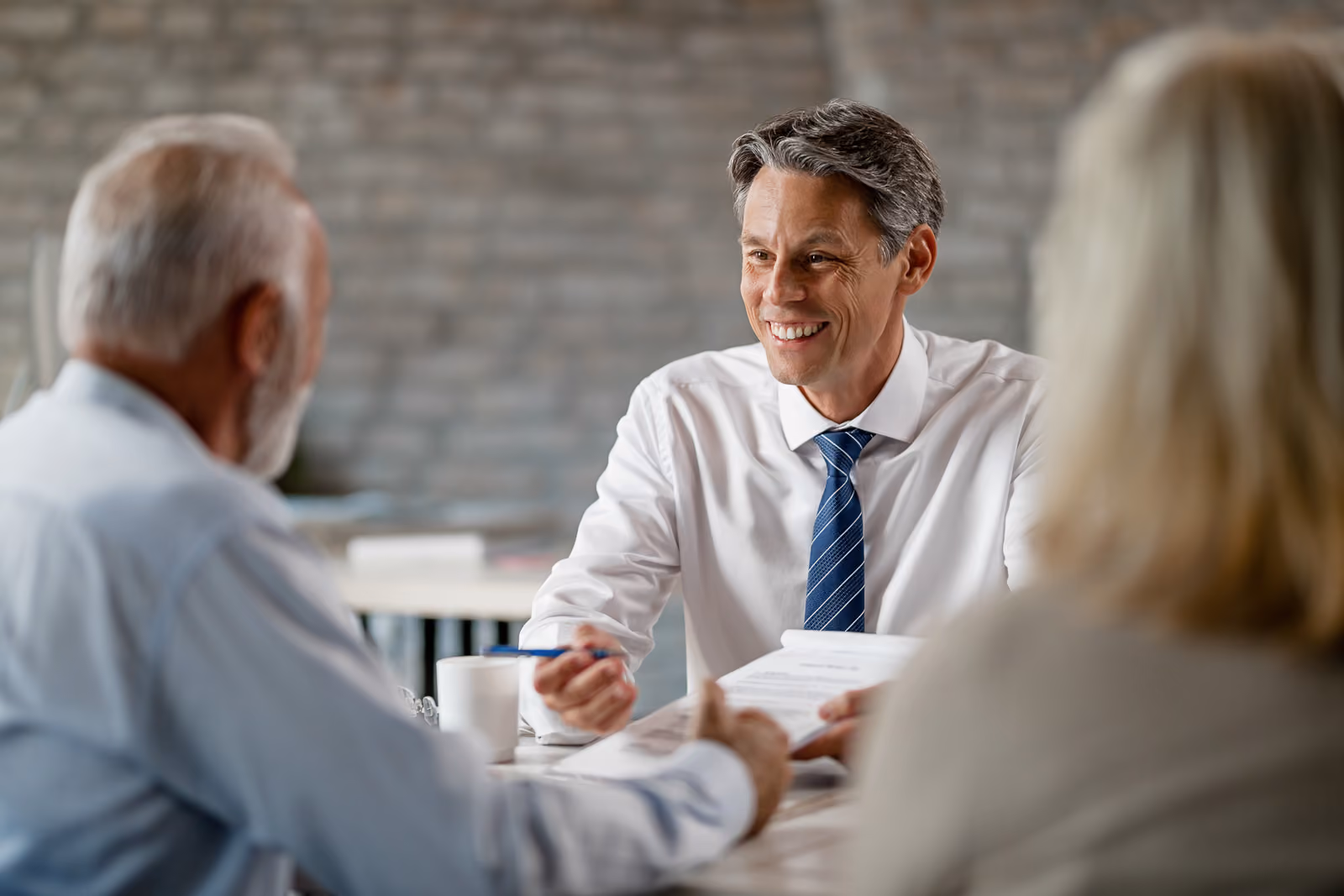 A man sitting at a table talking to a man and woman couple.