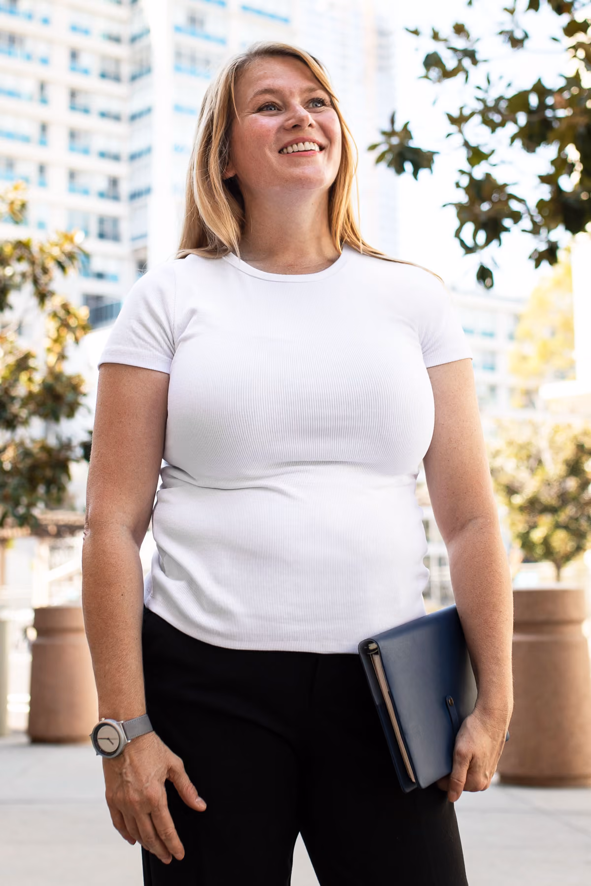 A woman in a white shirt is holding a folder.