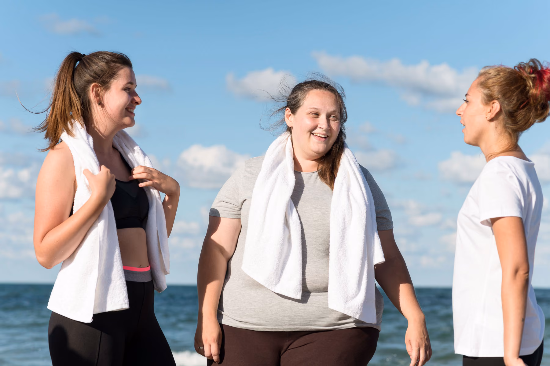 A group of women standing next to each other on a beach.