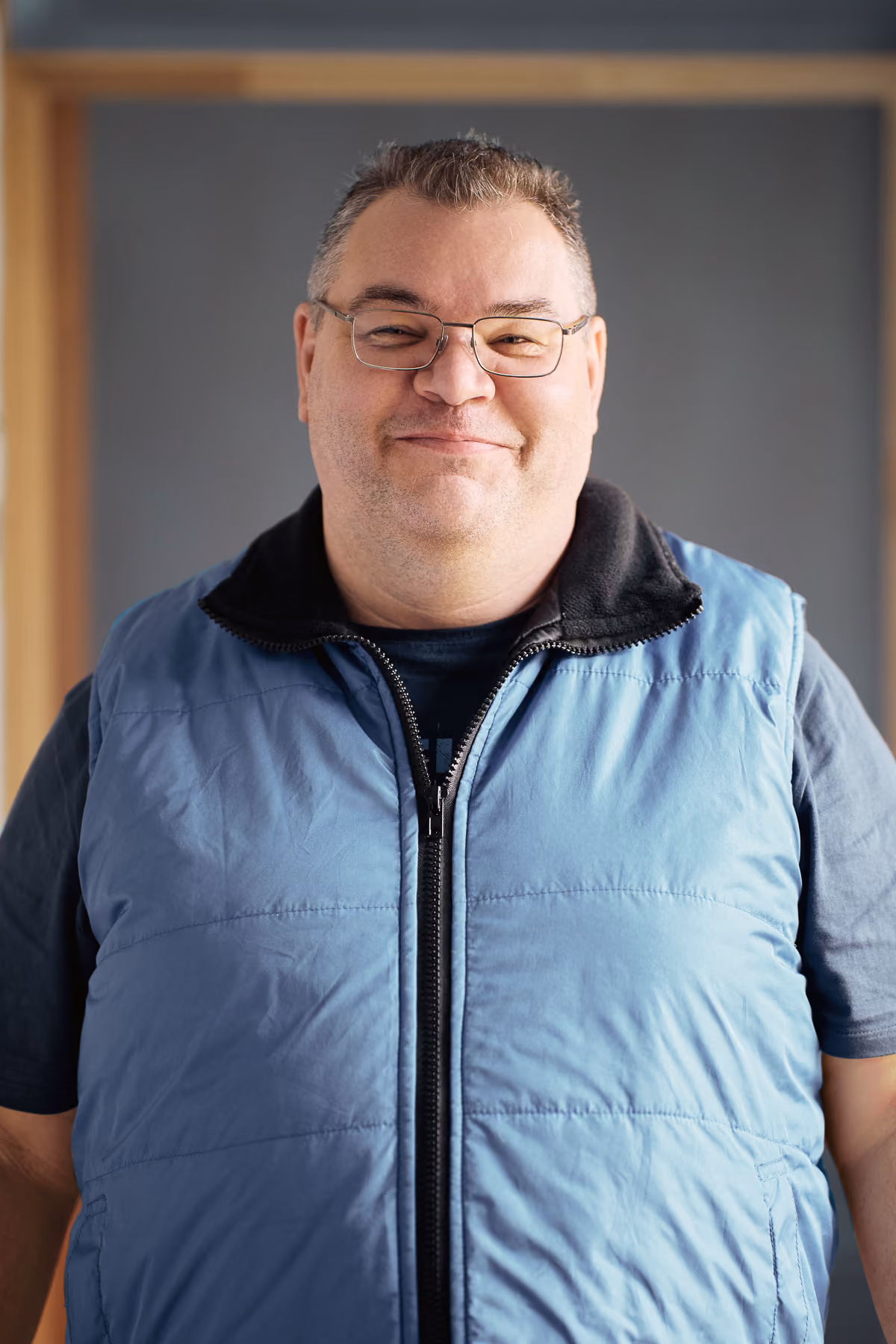 A man with glasses and a blue gilet.