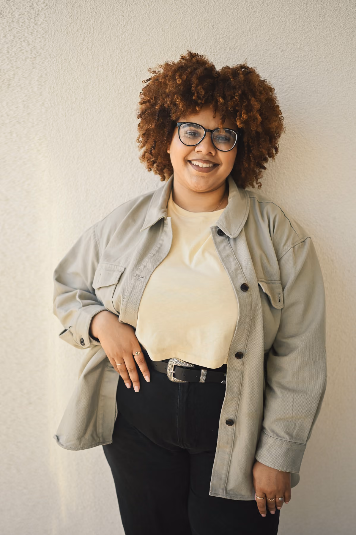 A woman with curly hair and glasses posing for a picture.