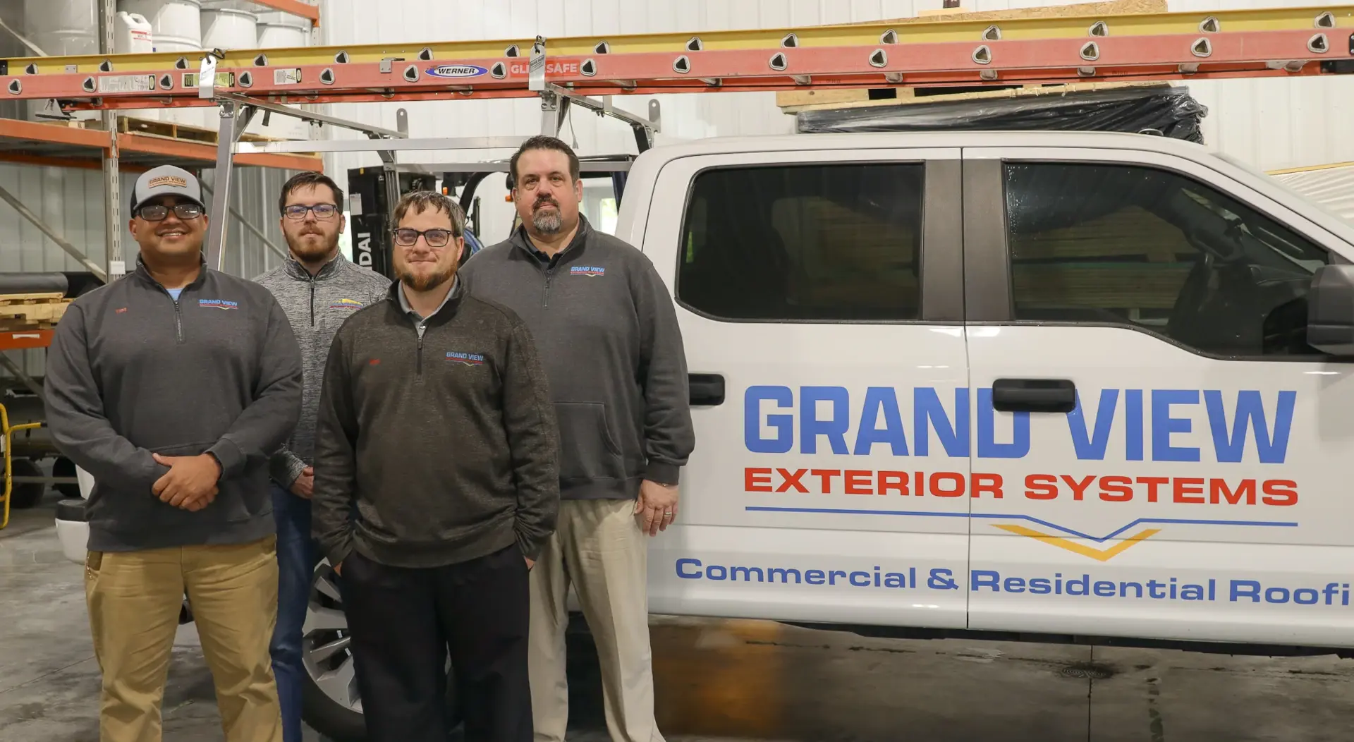 grand view group of four in front of brand truck in warehouse