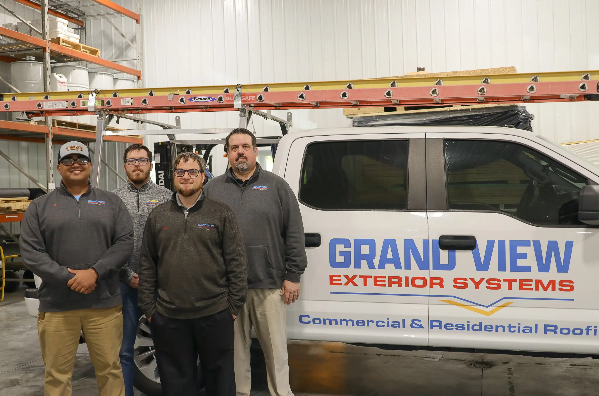 grand view group of four in front of brand truck in warehouse