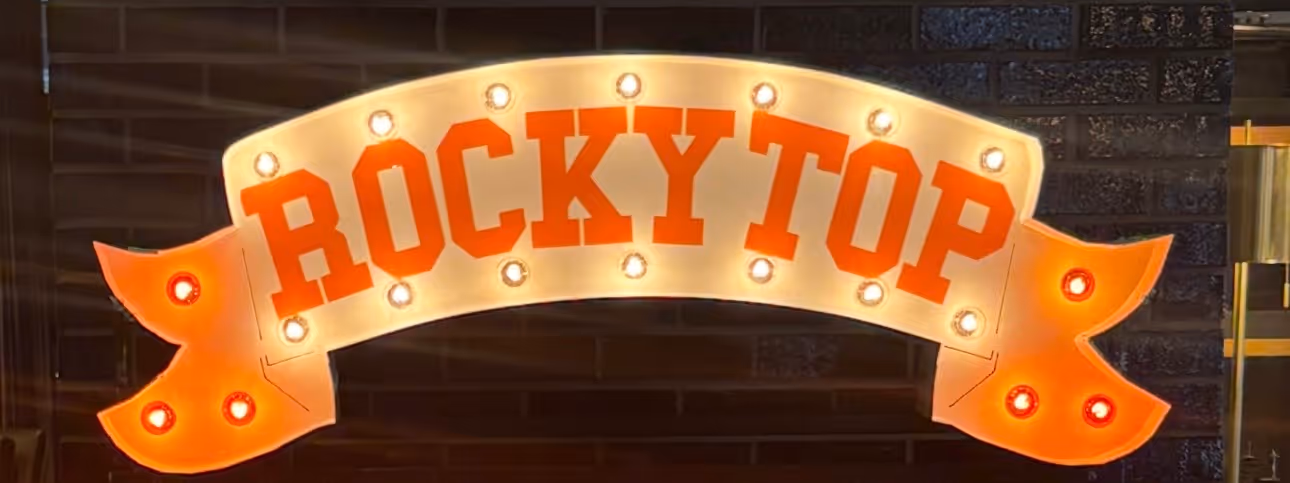 Lit letters spelling HVMS in front of silver and blue balloons at Hardin Valley Middle School with mural stars and music notes on the wall.