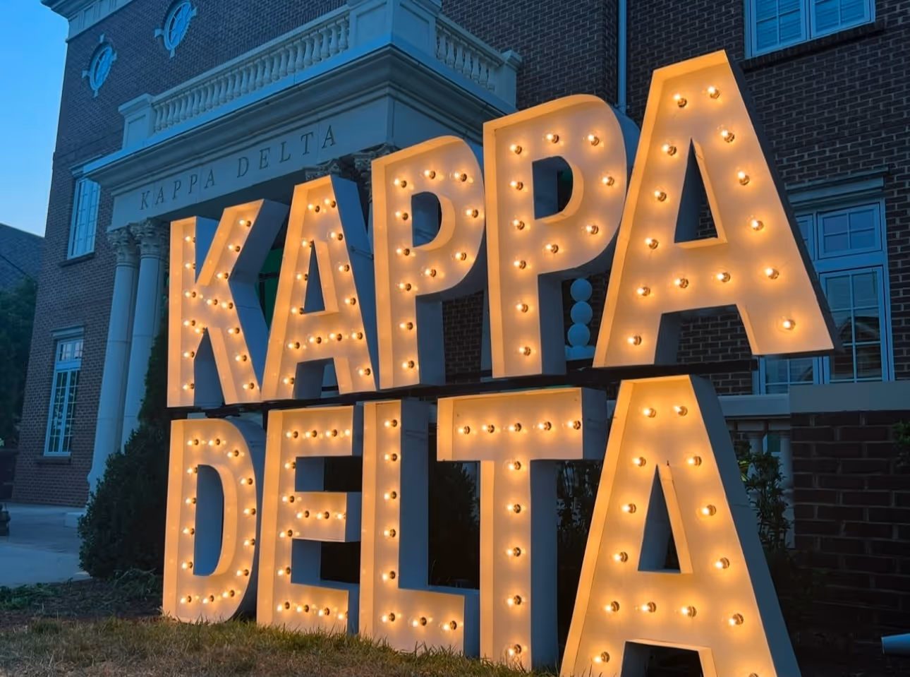Lit letters spelling HVMS in front of silver and blue balloons at Hardin Valley Middle School with mural stars and music notes on the wall.