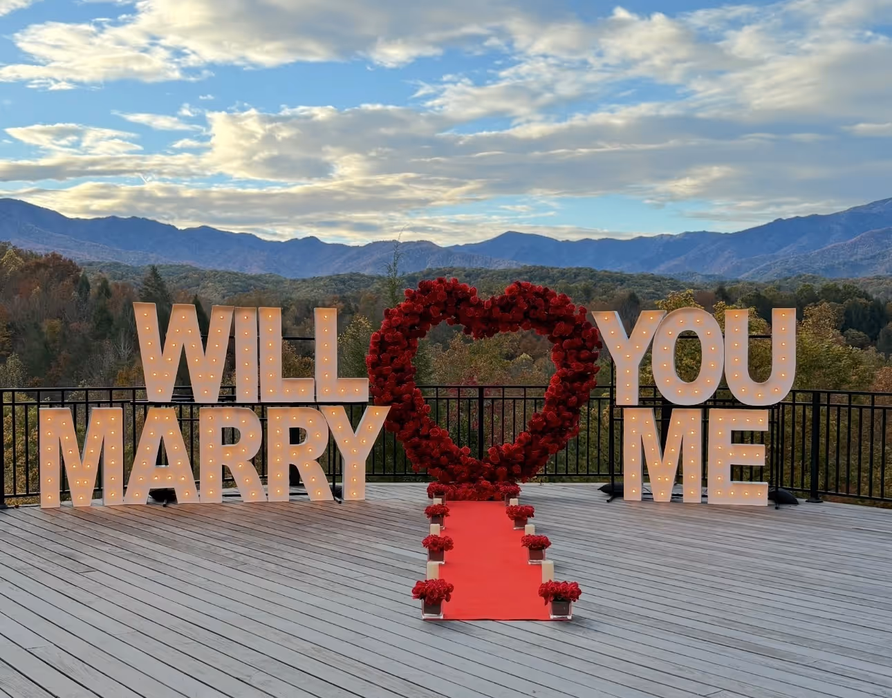Lit letters spelling HVMS in front of silver and blue balloons at Hardin Valley Middle School with mural stars and music notes on the wall.