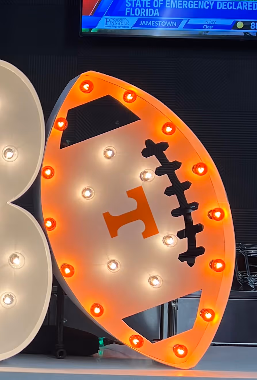 Lit letters spelling HVMS in front of silver and blue balloons at Hardin Valley Middle School with mural stars and music notes on the wall.