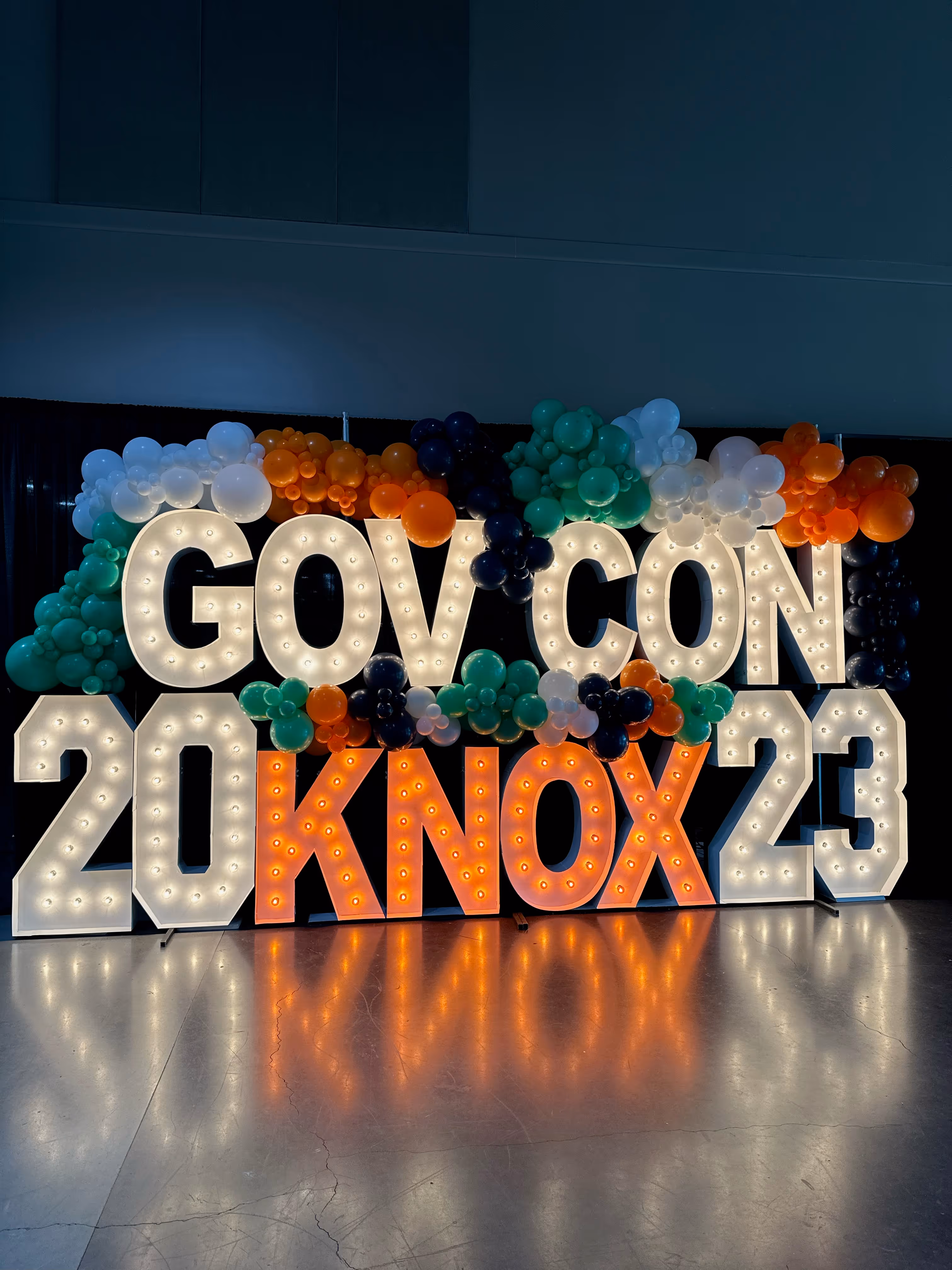 Lit letters spelling HVMS in front of silver and blue balloons at Hardin Valley Middle School with mural stars and music notes on the wall.