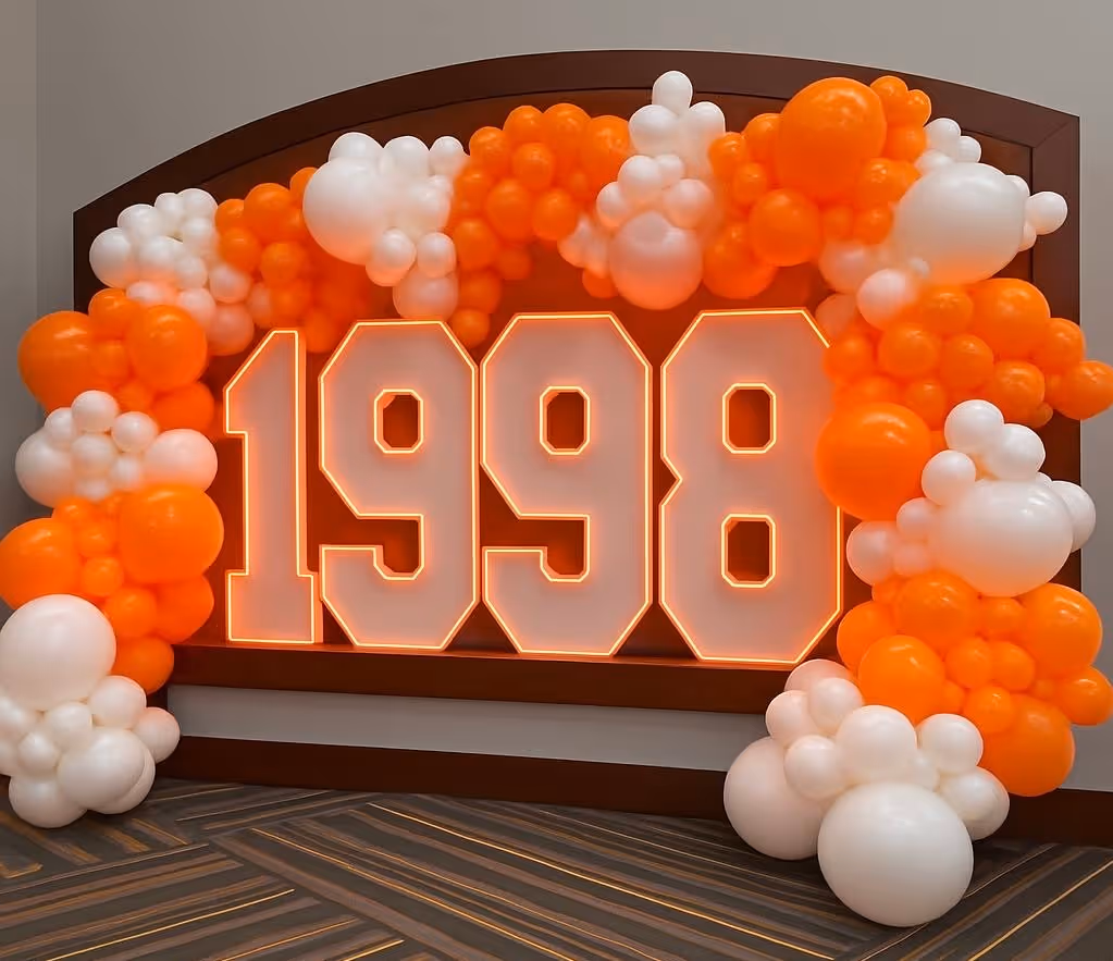 Lit letters spelling HVMS in front of silver and blue balloons at Hardin Valley Middle School with mural stars and music notes on the wall.