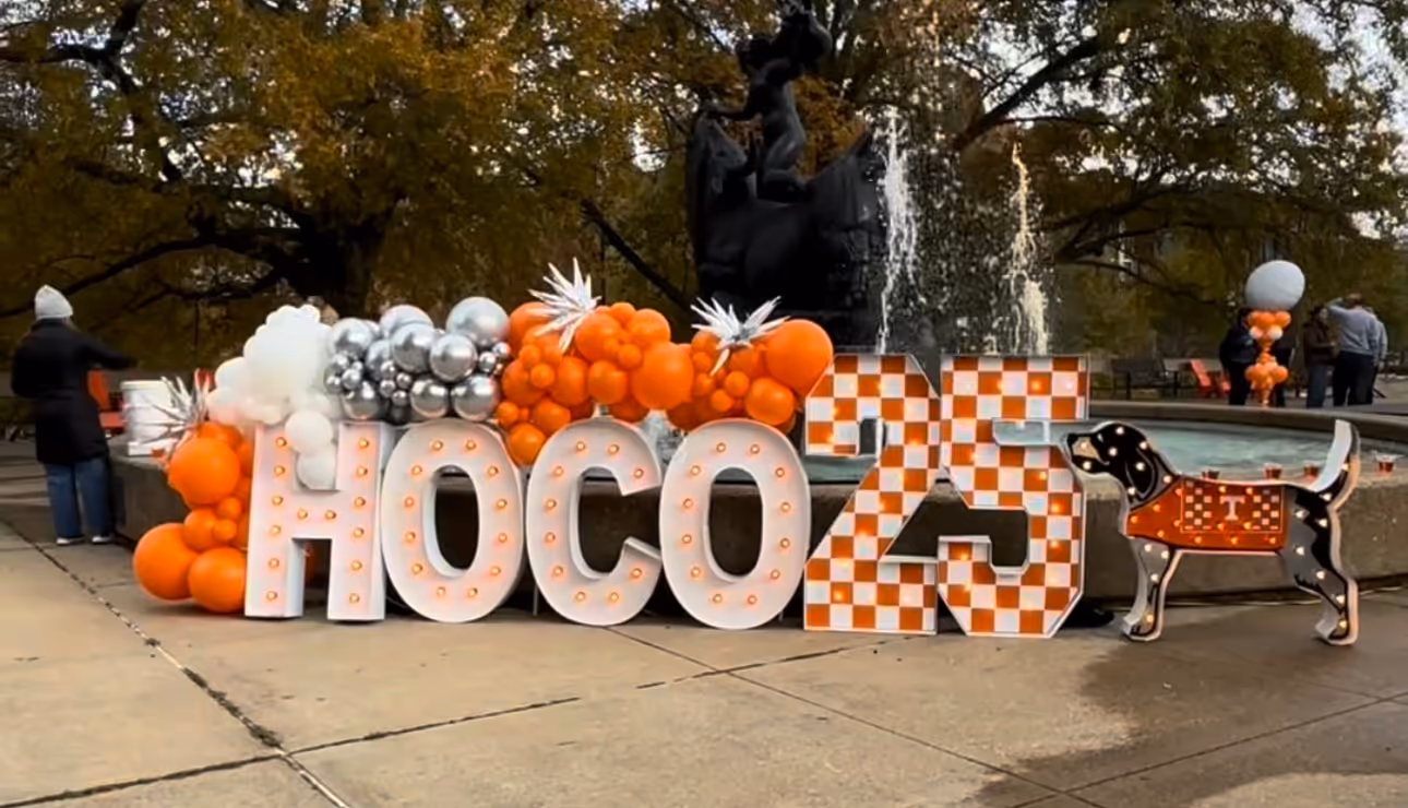 Lit letters spelling HVMS in front of silver and blue balloons at Hardin Valley Middle School with mural stars and music notes on the wall.