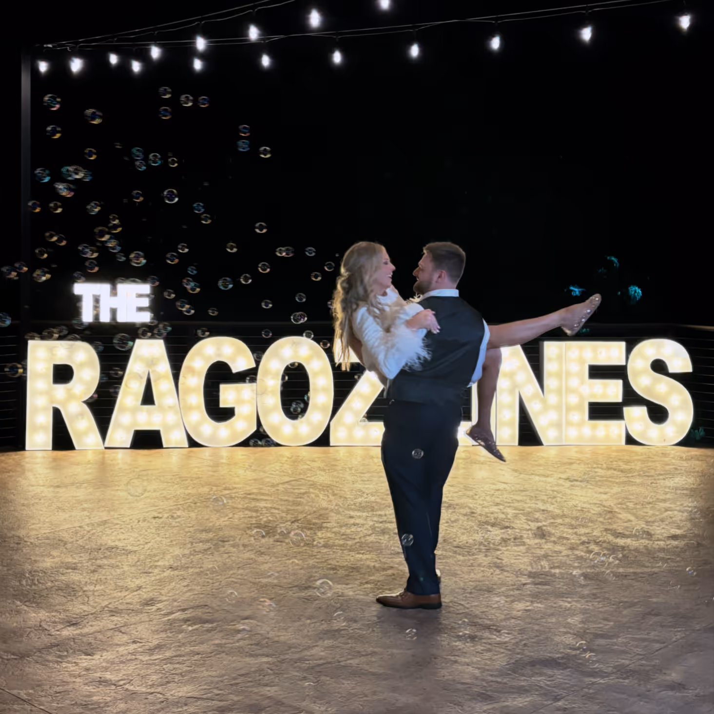 Lit letters spelling HVMS in front of silver and blue balloons at Hardin Valley Middle School with mural stars and music notes on the wall.