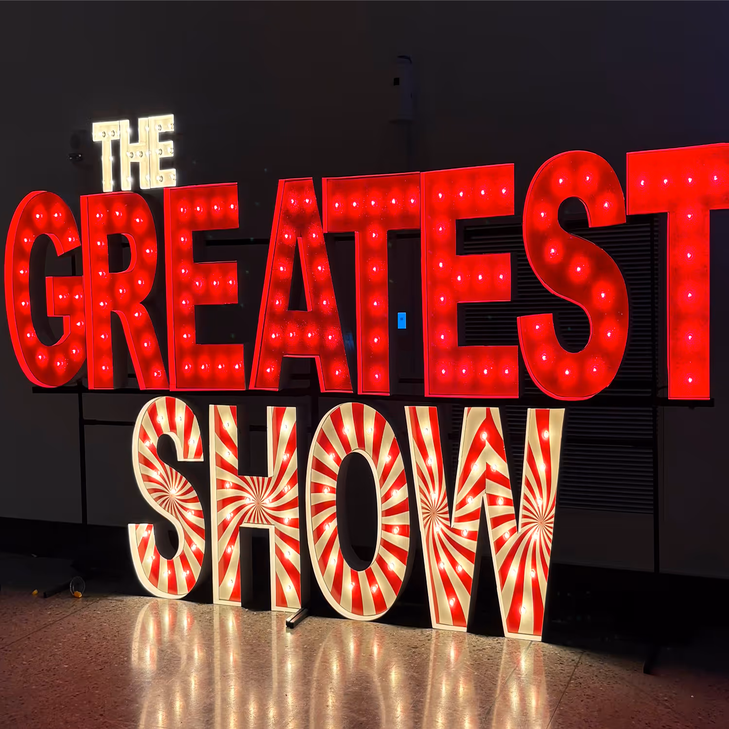 Lit letters spelling HVMS in front of silver and blue balloons at Hardin Valley Middle School with mural stars and music notes on the wall.