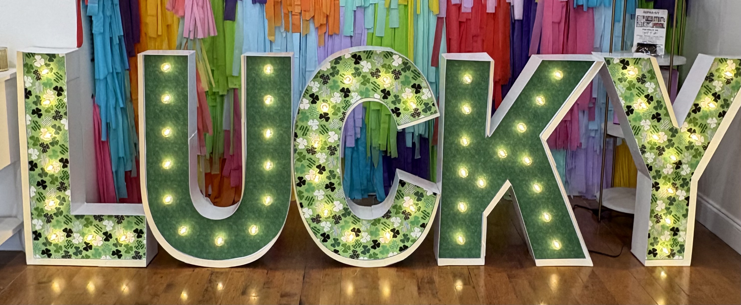 Lit letters spelling HVMS in front of silver and blue balloons at Hardin Valley Middle School with mural stars and music notes on the wall.