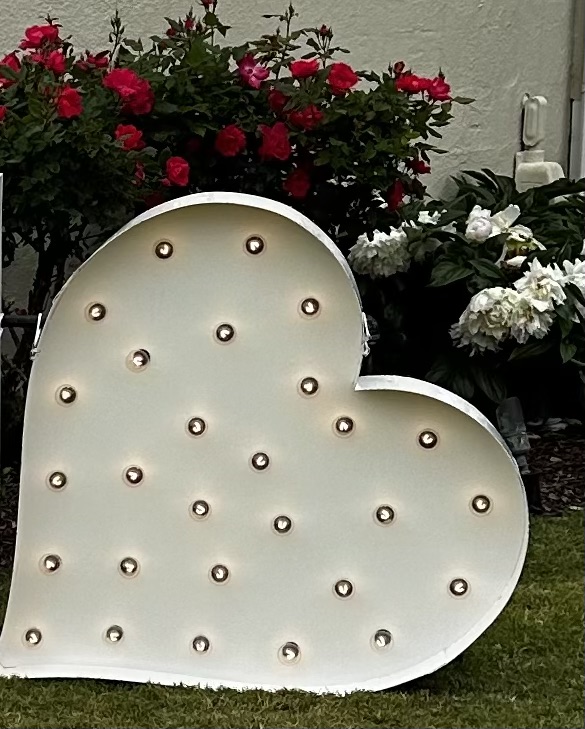Lit letters spelling HVMS in front of silver and blue balloons at Hardin Valley Middle School with mural stars and music notes on the wall.