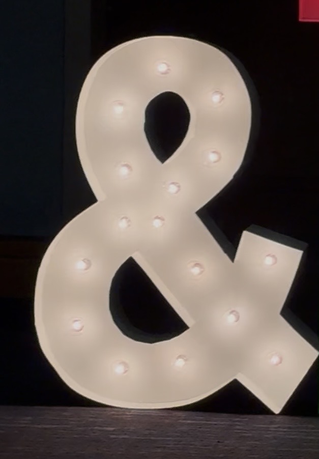 Lit letters spelling HVMS in front of silver and blue balloons at Hardin Valley Middle School with mural stars and music notes on the wall.