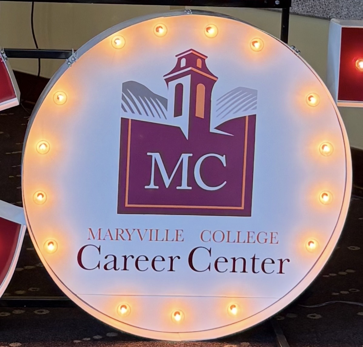 Lit letters spelling HVMS in front of silver and blue balloons at Hardin Valley Middle School with mural stars and music notes on the wall.