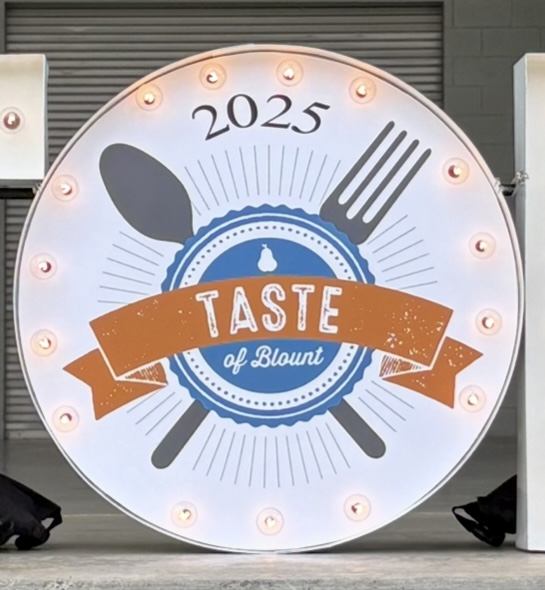 Lit letters spelling HVMS in front of silver and blue balloons at Hardin Valley Middle School with mural stars and music notes on the wall.