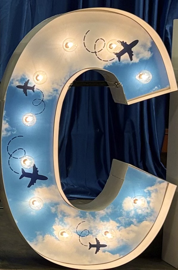 Lit letters spelling HVMS in front of silver and blue balloons at Hardin Valley Middle School with mural stars and music notes on the wall.