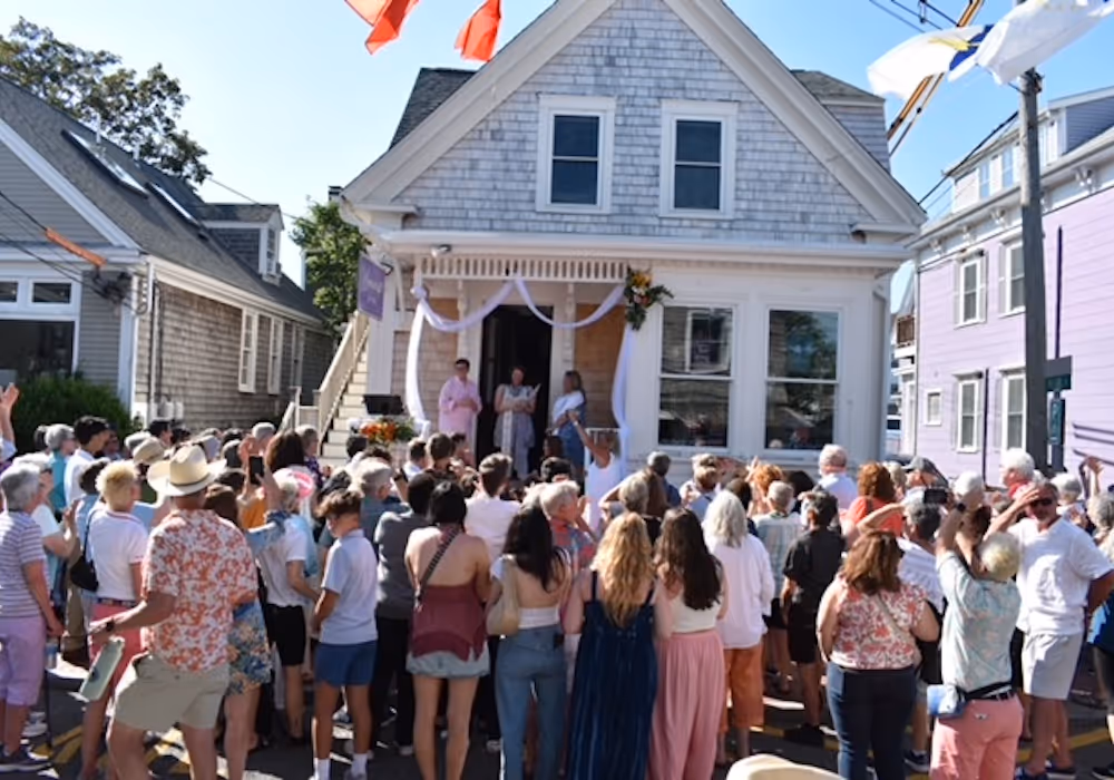 Lesbian wedding held on the front steps of Womencrafts Provincetown while a large audience watches