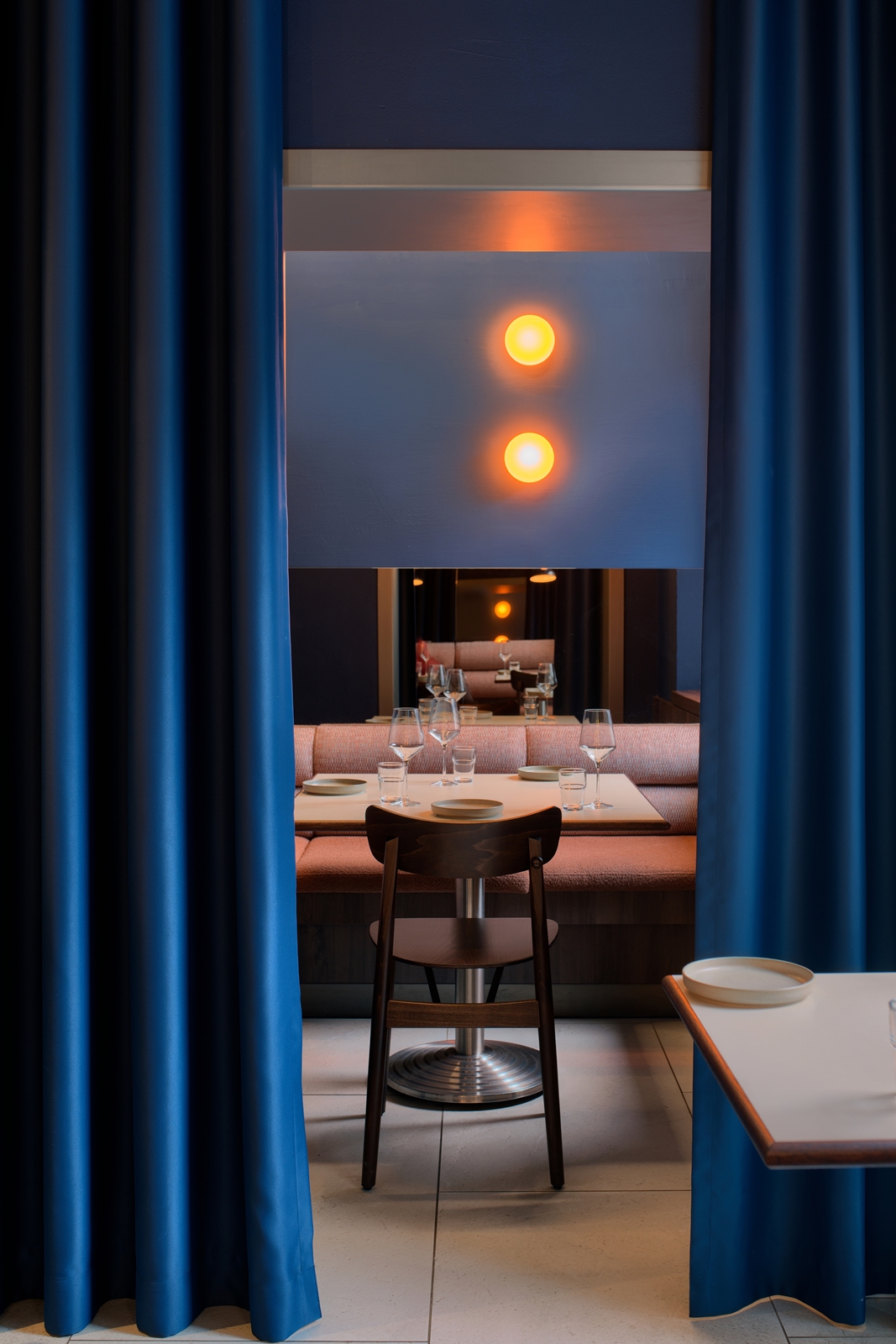 Rows of hanging crystal wine glasses with warm ambient lighting in a bar setting.