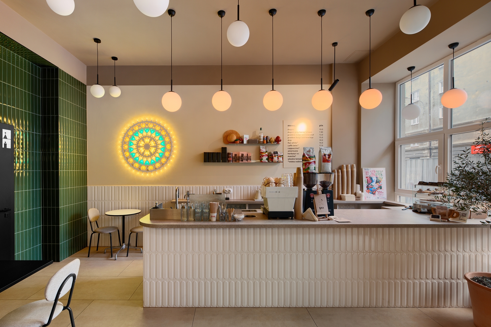 Cozy restaurant interior with cushioned bench seating, wooden chairs, tables set with plates and glasses, and a wine bottle display with hanging lights.