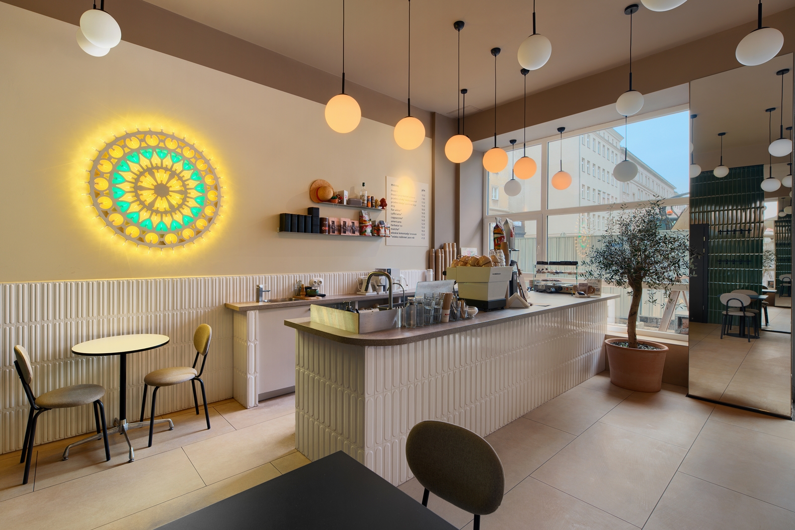 Modern cafe interior with marble tables, orange-framed brown chairs, green bench seating, and a colorful floral mural on the wall.