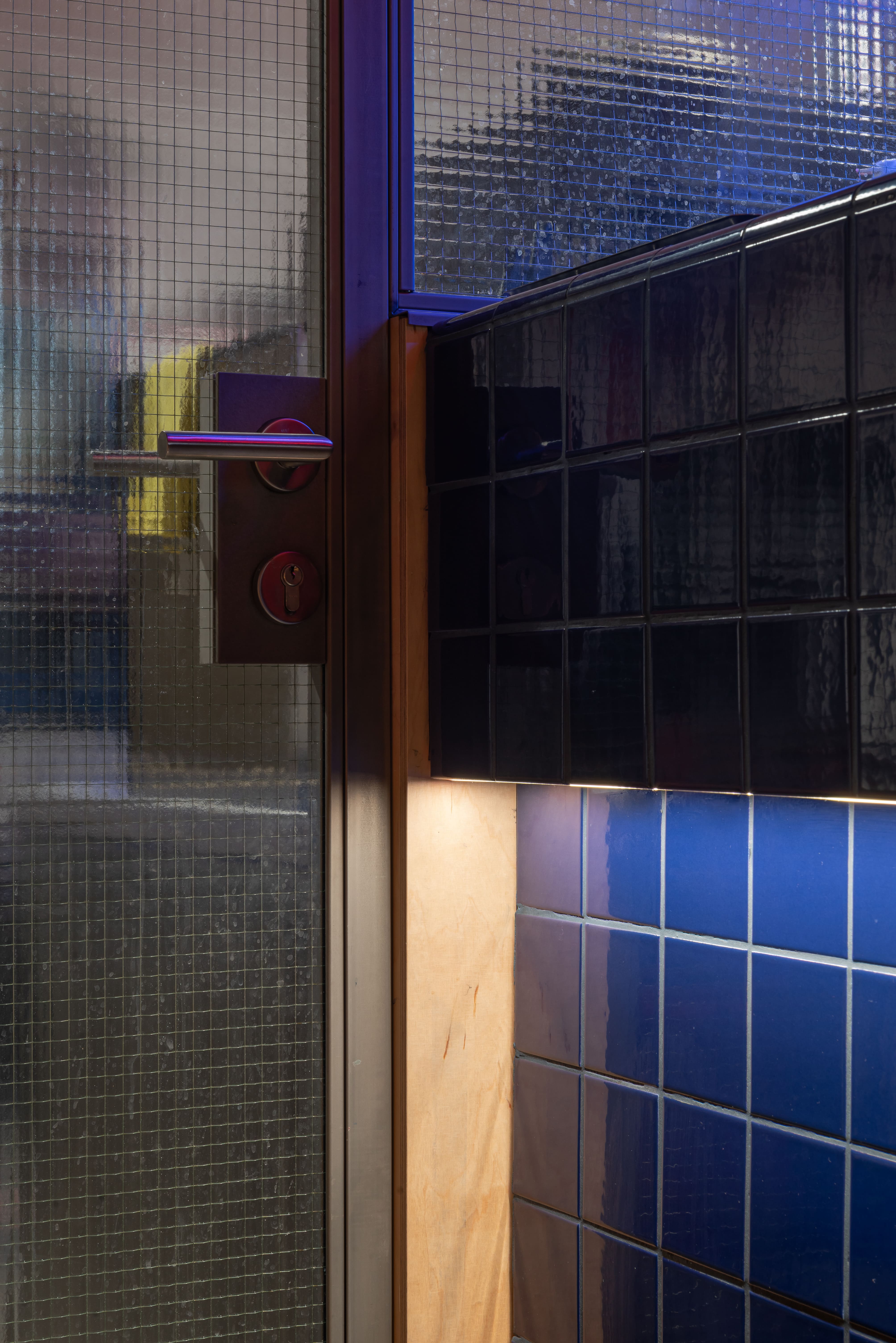 Interior of a bar with a neon circular sign reading 'MEDUSA', five tall stools, and shelves stocked with bottles and glassware.