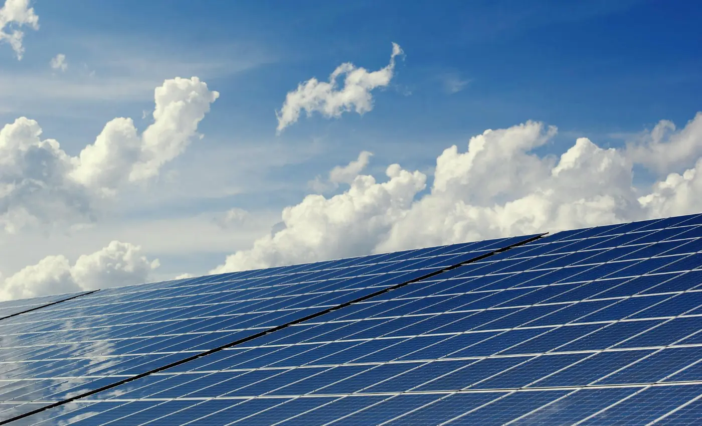 Solar panels against a blue sky with clouds.