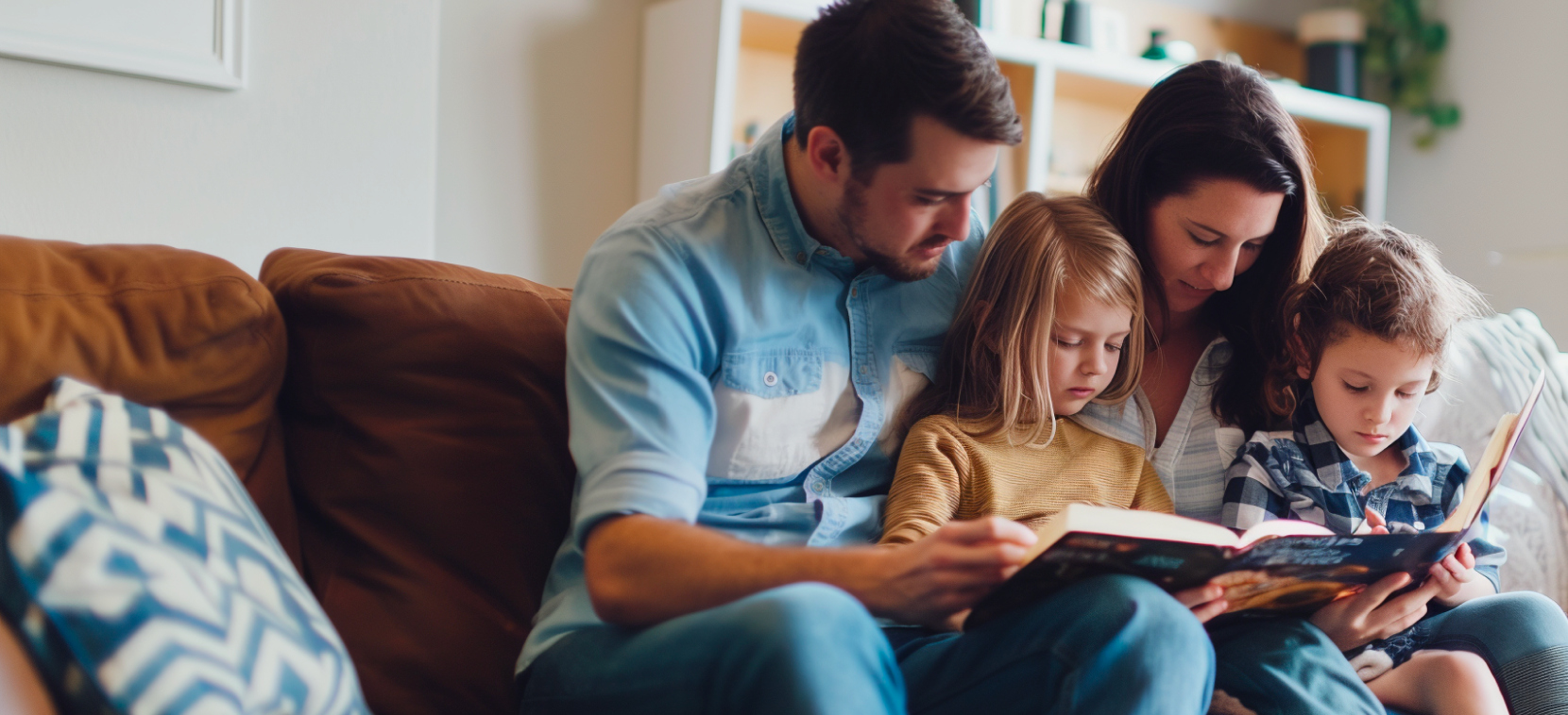 A family sitting on a couch reading a book.