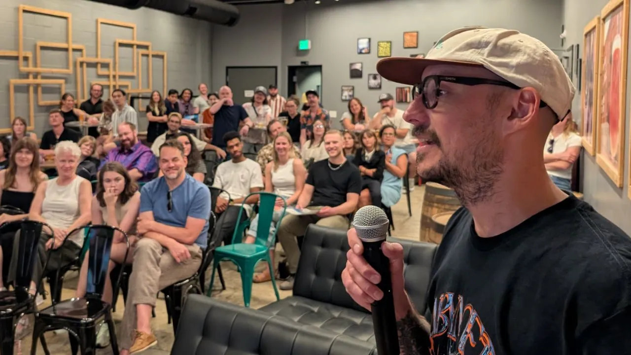 Co-founder of Side Hustle Film Fest, CJ Coccia, holding a microphone talking to the audience