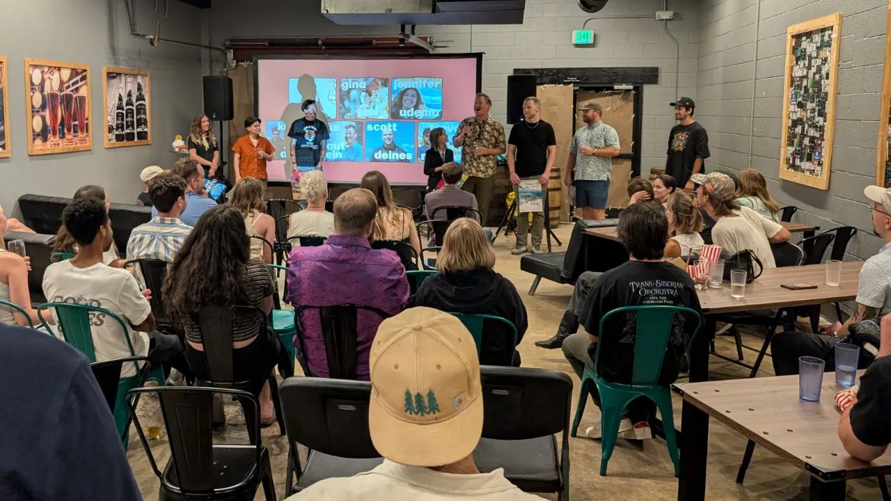 An audience asks questions for the Side Hustle Film Fest 2025 filmmakers standing in front of the movie screen