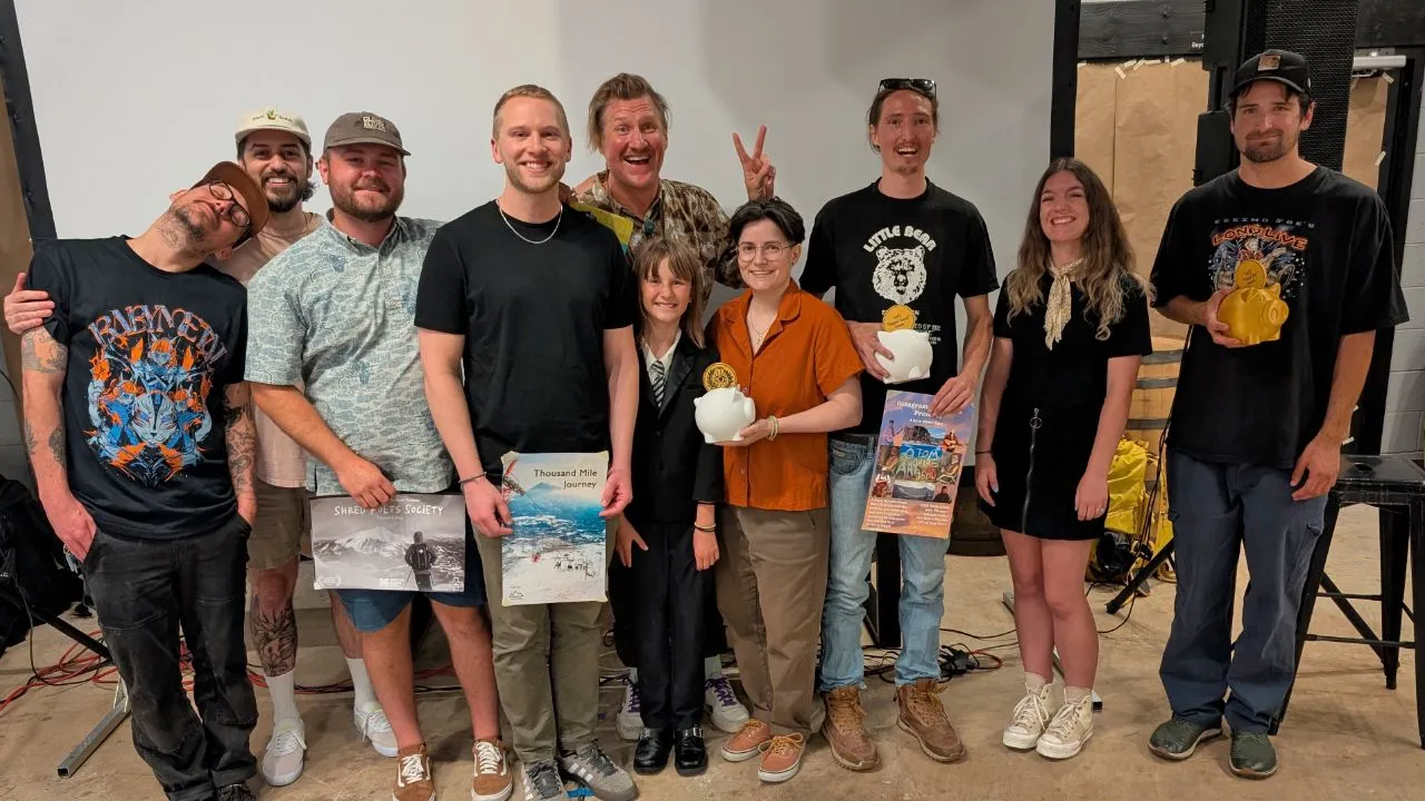 A group photo of Side Hustle Film Fest 2025 filmmakers and owners. From left to right: CJ Coccia, Adam Raiola, Trevor Schumacher, Scott Deines, Luke Trautwein, Pearl Trautwein, Gina Valvo, Andy Olson, Jennifer Udema, and Kavon Zamanian standing in front of the movie screen