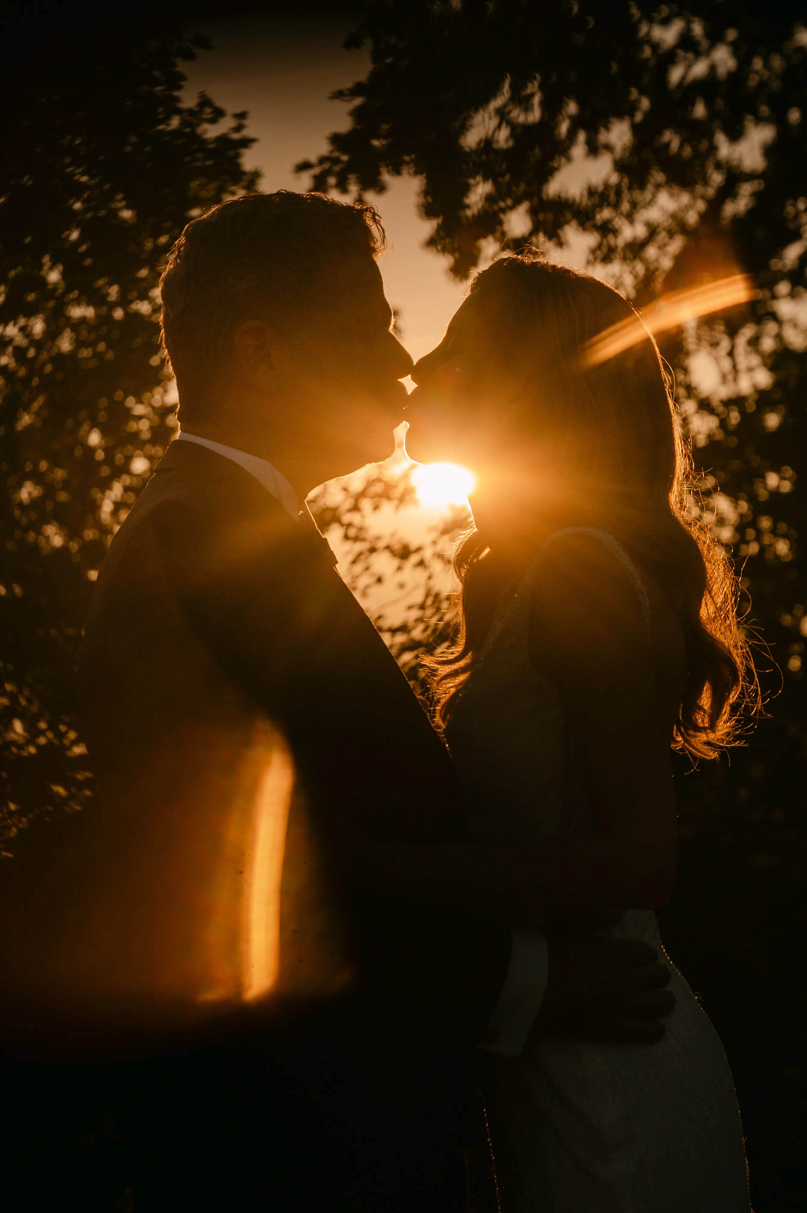un couple qui s'embrasse avec un coucher de soleil en arrière plan