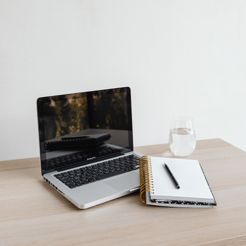 Laptop on a desk with a notebook