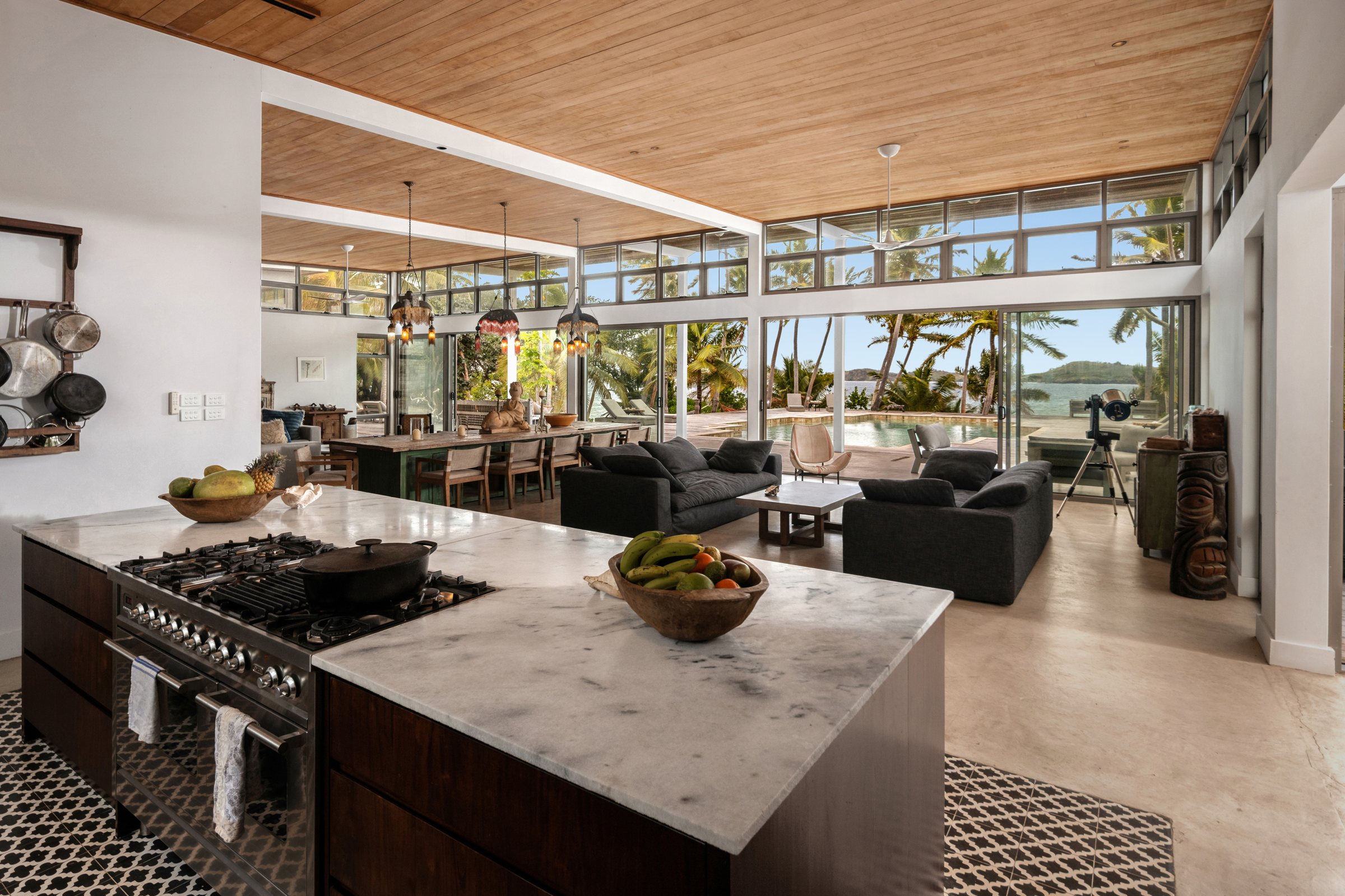 Marble kitchen island opening onto the living and dining room with ocean views