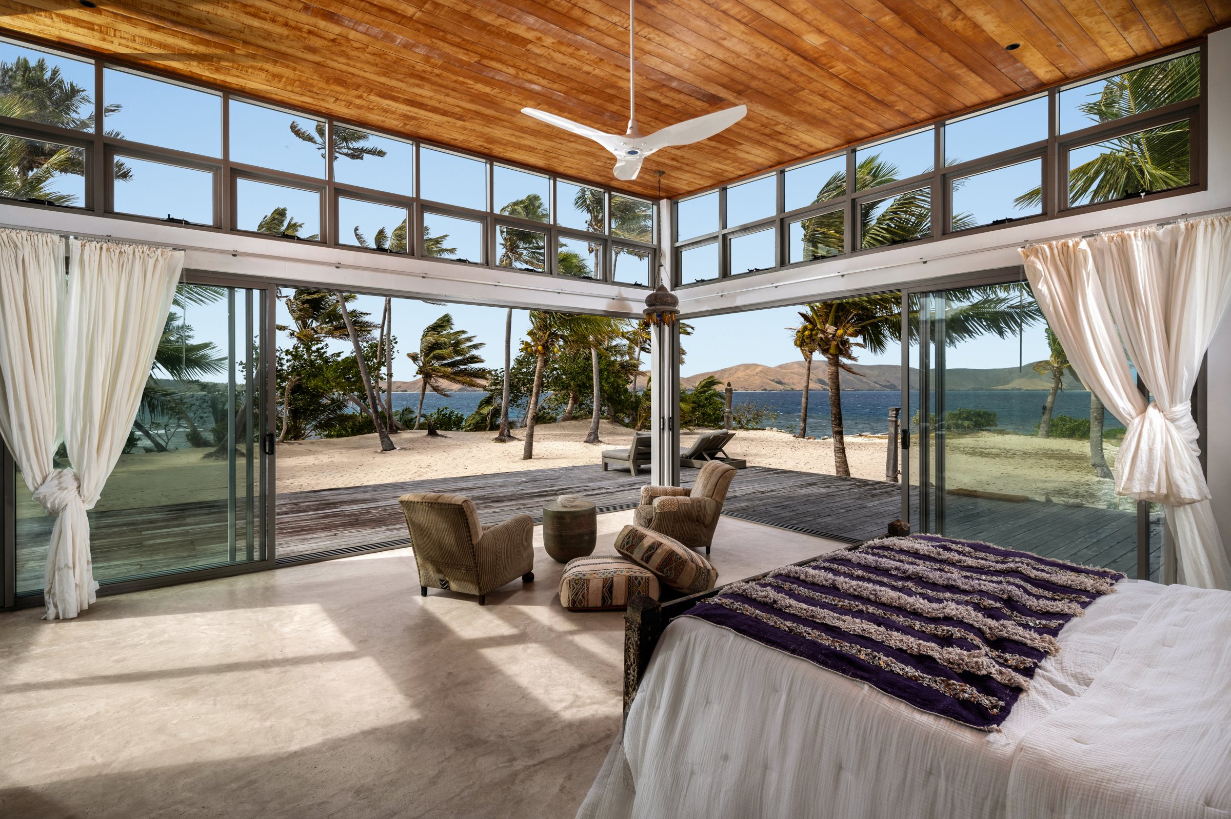 Bedroom with wood ceiling and clerestory windows opening fully onto the beach and ocean