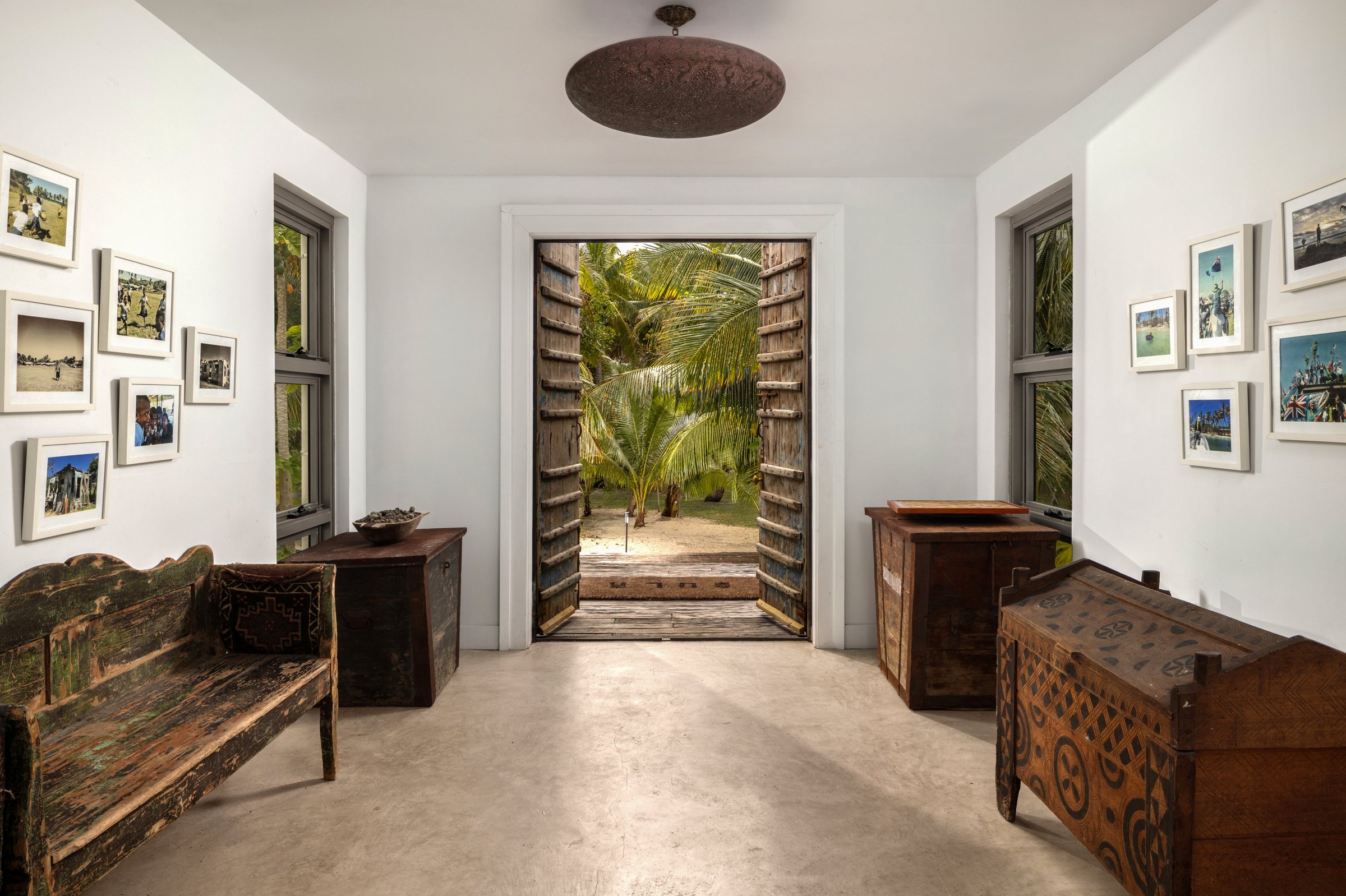 Entry hall with carved chests and antique wooden doors opening to the palm garden