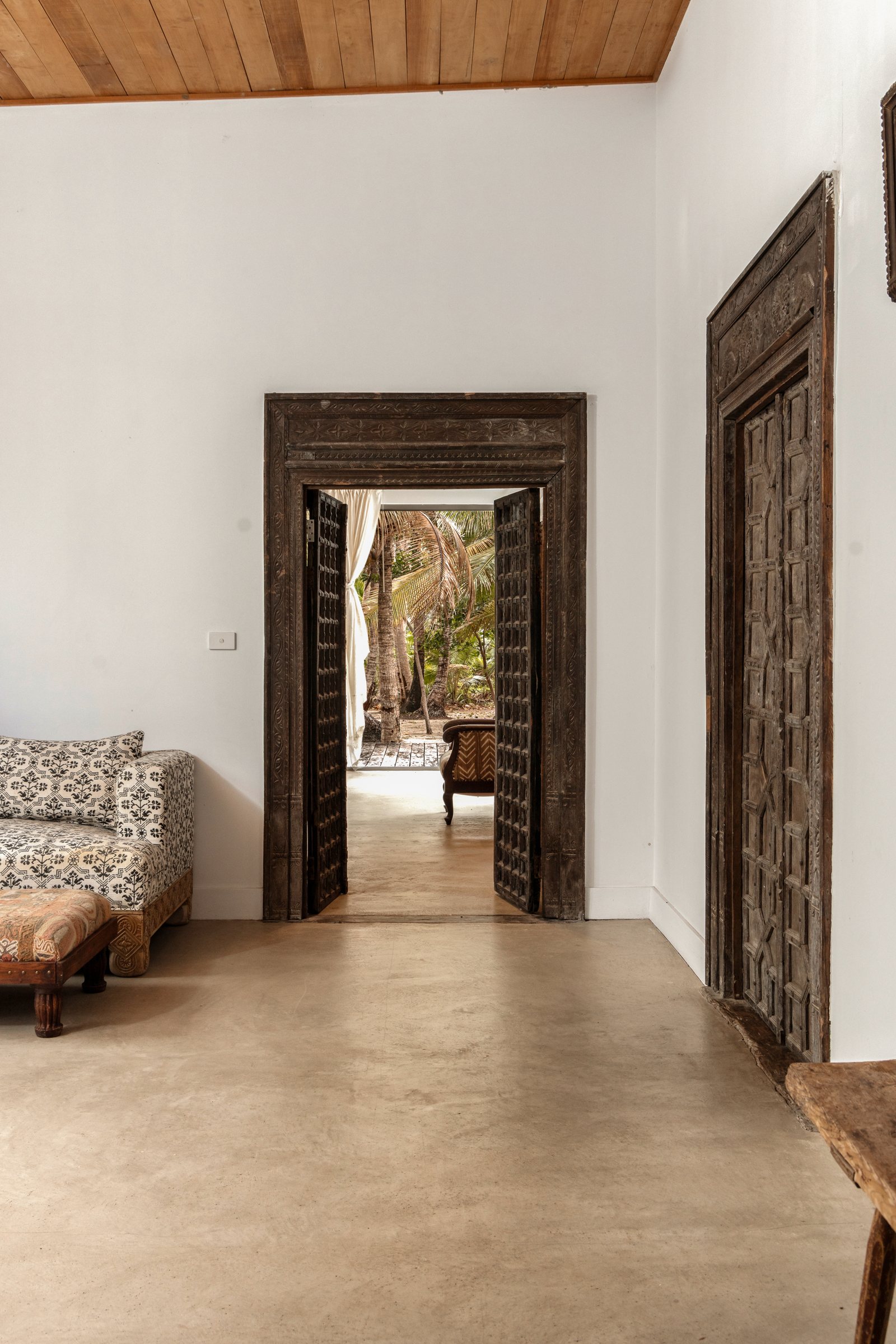 Carved wooden doorway framing a view through to the palms