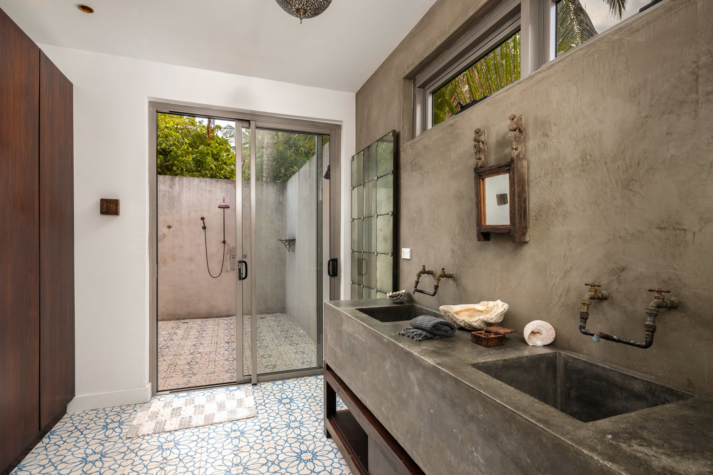 Bathroom with polished concrete double sink and glass doors to an outdoor shower