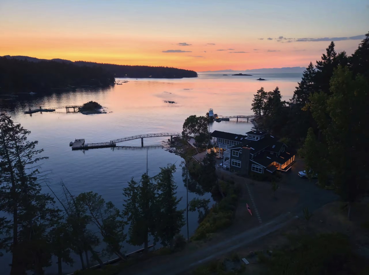 The estate lit up at twilight above Whaler's Bay, with the dock and a sunset over the islands