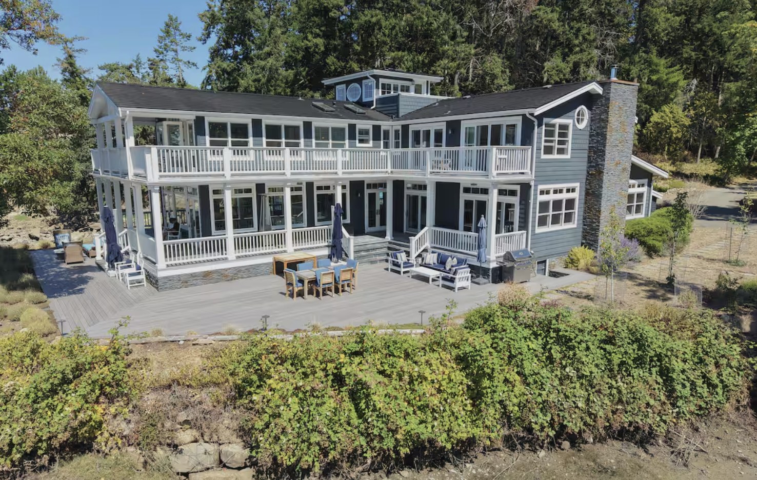 The two-story house with white wraparound verandas and a large terrace with dining and lounge seating